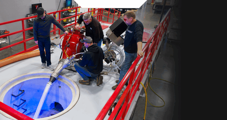4 crew members performing a sewer inspection with a large machine with piping into a hole